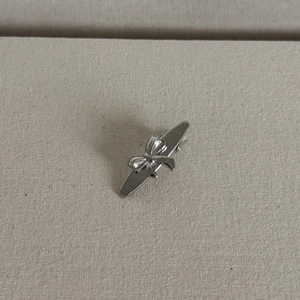 Elegant silver brushed metal bow hair clip with a polished finish on textured background