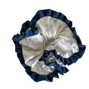 Elegant white floral scrunchie with blue ruffled edges for stylish bun hairstyles