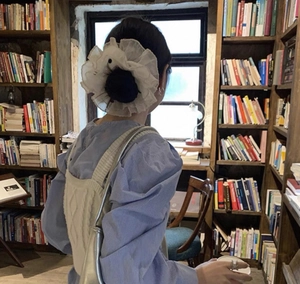Rear view of a model wearing a white layered organza scrunchie with romantic ruffle details
