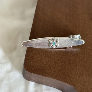 Detail of silver vintage flower hair clip with blue crystal and brushed metal finish