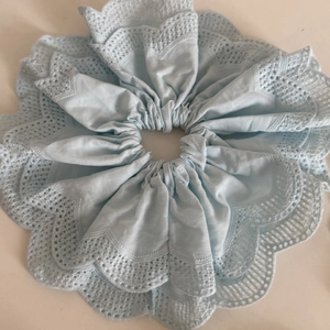 Détail macro d'un grand chouchou bleu clair avec une élégante broderie en dentelle double