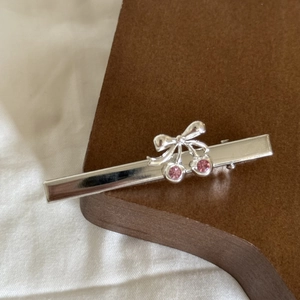 Detail view of silver vintage hair clip with bow shape and pink crystal cherry accents