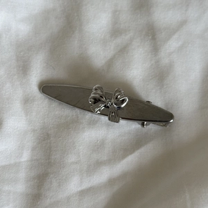 Close-up of a vintage silver flower hair clip with a 3D bow on a white fabric background