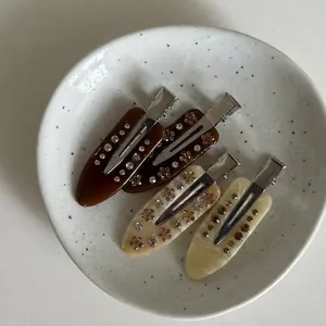 Set aus vier Haarklammern aus Acetat mit Marmormuster und Strassbesatz auf einem Teller