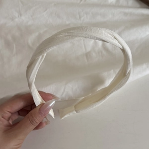 Close-up of white twisted headband with pleated fabric texture and non-slip design