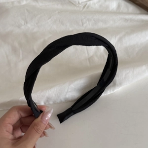 Detail view of black twisted fabric headband featuring inner anti-slip teeth design