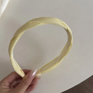 Detail view of a yellow twisted fabric headband with internal anti-slip teeth