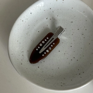 Detailansicht der Haarspange aus braunem Acetat mit Strasssteinen und Marmormuster