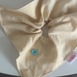 Detail of cream polka dot hair scrunchie with blue flower button and handmade label
