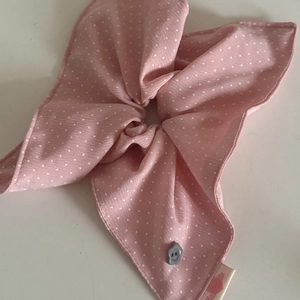 Detail of pink polka dot bow scrunchie with a smiley button and handmade woven label