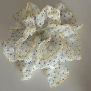 Detail of floral chiffon scrunchie with yellow scalloped edges and pleated texture