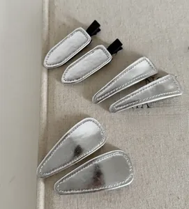 Detail view of silver metal triangle and drop hair clips on a textured fabric book cover