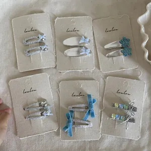 Detail view of various blue and silver hair clips on a linen display card packaging