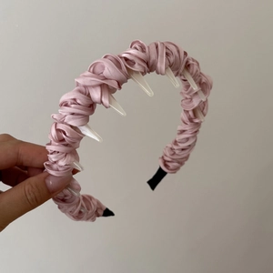 Dettaglio del cerchietto in raso rosa con denti bianchi per una tenuta sicura e stile