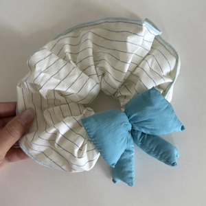 Chouchou rayé bleu et blanc avec nœud bleu doux sur un fond blanc épuré