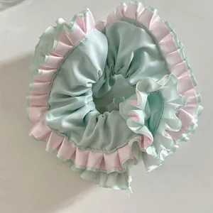 Detail of satin floral scrunchie in mint green and pink with ruffled lace design