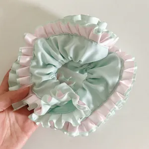 Detailed close-up of large satin scrunchie with pastel pink and mint green lace
