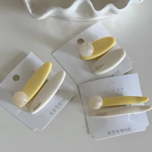 Close-up of macaron cream yellow hair clips with Nuance engraving on display cards