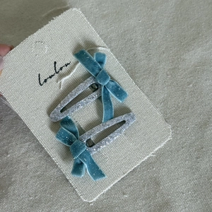 Detail of teal velvet bows on silver glitter hair clips pinned to product display card