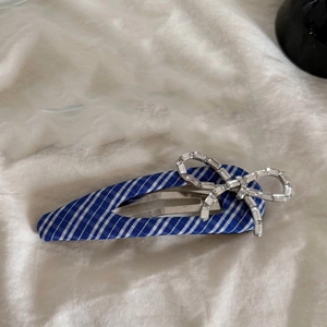 Gros plan d'une barrette à rayures bleues et blanches avec un nœud en strass étincelants