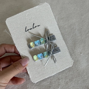 Close-up of silver bow hair clips with blue heart rhinestones on a white display card