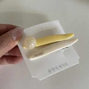 Detail of macaron yellow and cream hair clips set on a branded display card