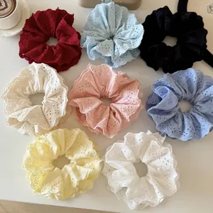Huit chouchous en dentelle colorée avec broderie florale disposés sur un fond blanc