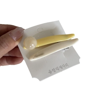 Two-piece macaron cream hair clip set in yellow and beige on display card