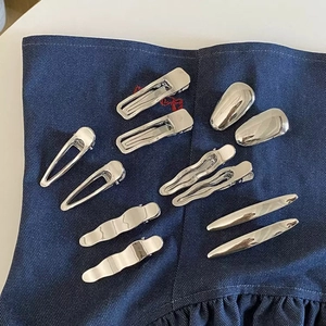Set of minimalist silver metal hair clips in geometric shapes on blue denim fabric