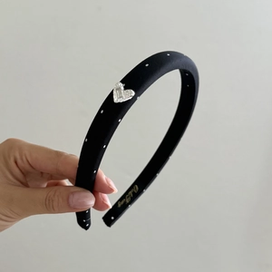 Narrow black fabric headband with white polka dots and silver rhinestone heart buckle