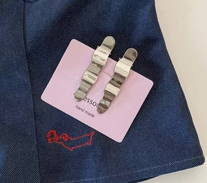 Detail of silver wavy metal hair clips with polished finish on denim fabric background