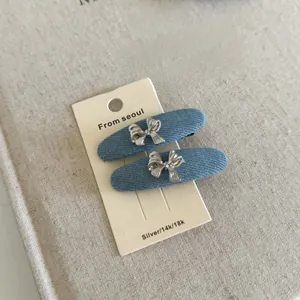Dettaglio di fermagli in denim con fiocchi in metallo argentato su carta da esposizione