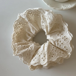 Détail d'un chouchou en dentelle anglaise crème avec broderie florale et bords ondulés