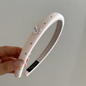 Close-up of pink polka dot headband featuring silver heart with a purple gemstone