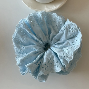 Vue détaillée du chouchou en dentelle bleu clair avec broderie florale et bords ondulés