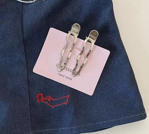 Detail of silver wavy metal hair clips with hammered texture on denim background