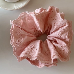 Détail du chouchou en dentelle rose avec broderie anglaise et bords à volants soyeux