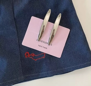 Detail of silver metallic duckbill hair clips displayed on a pink card over denim fabric