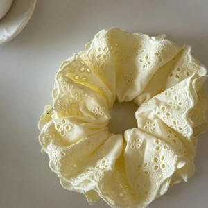 Gros plan détaillé du chouchou en dentelle jaune clair avec broderies et bords ondulés