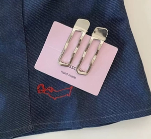 Close-up of dual silver rectangular hollow hair clips on a pink display card