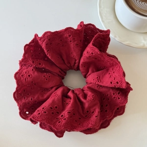 Gros plan d'un chouchou en dentelle rouge foncé brodée à côté d'une tasse de café