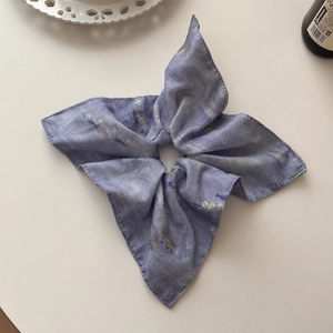 Detailed macro view of the light purple floral silk bow scrunchie on a white table