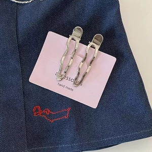 Pair of minimalist wavy silver metal hair clips with textured finish on display card
