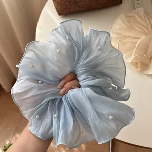 Detail of light blue pleated mesh scrunchie with white pearl accents on fabric