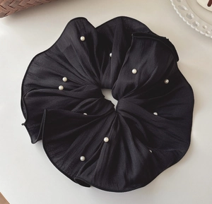 Close-up of black mesh scrunchie with pleated texture and delicate white pearls