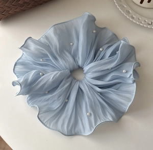 Detail of light blue mesh scrunchie with pleated texture and white pearl embellishments