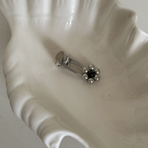 Detailed macro view of silver flower hair clip with black bead center on white shell tray