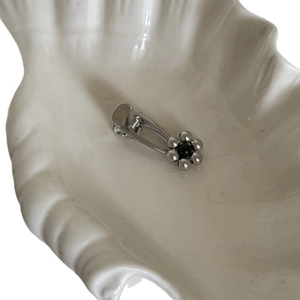 Elegant silver metal flower hair clip with black bead accent on a white ceramic shell
