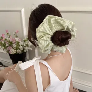 Oversized green and white plaid scrunchie hair tie shown in a natural lifestyle setting