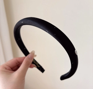 Detailed macro view of black satin headband with silver sparkles and Love metal charm
